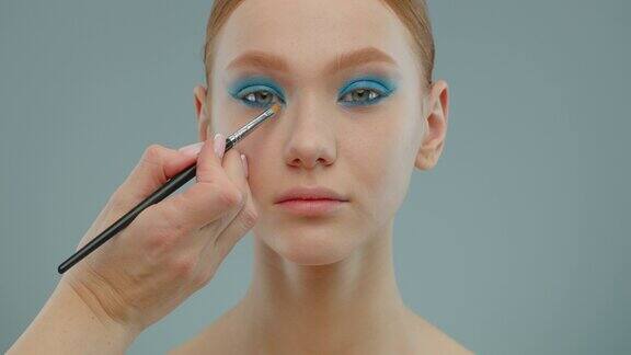 化妆师的手将化妆品涂抹在女孩的眼睛上