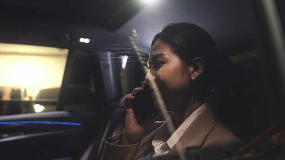 女人在晚上开车穿过城市回家时用手机