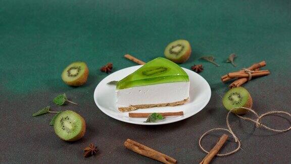 自制芝士蛋糕配猕猴桃白色盘子绿色背景装饰以猕猴桃片肉桂棒和薄荷叶本空间