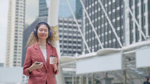 商务往返东南亚女商人使用耳机与智能设备的背景建筑城市城市