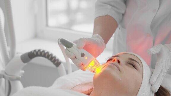 红色LED处理女子做面部皮肤治疗射频整容硬件抗老化程序射频提升和真空按摩美容师正在进行美容手术
