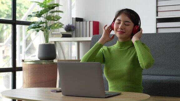 年轻放松微笑的漂亮女人放松地坐在家里的沙发上女性在舒适的沙发上享受音乐带来的快乐高品质4k画面