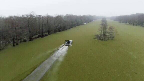 无人机拍摄的一艘飞艇在路易斯安那州南部的阿查法拉亚河流域沼泽中快速通过漂浮的Salvinia(蕨类植物)
