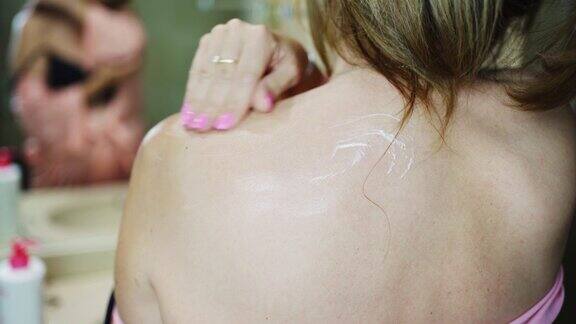 白人妇女在她的背上涂保湿霜护肤