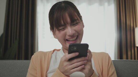 一个年轻的亚洲妇女使用智能手机笑得很开心