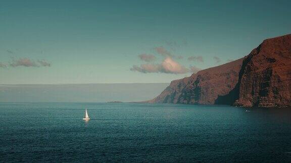 孤独的游艇在海湾附近的山脉特内里费加那利岛暑假风景的洛斯吉甘斯悬崖岩石海岸