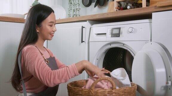 快乐的亚洲年轻女子正在家里洗衣服