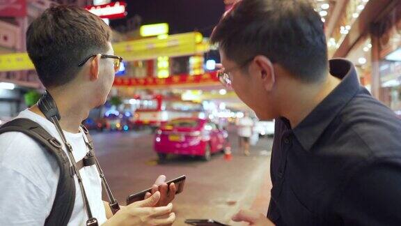 两个亚洲男人在街头夜市用手机看地图寻找方向