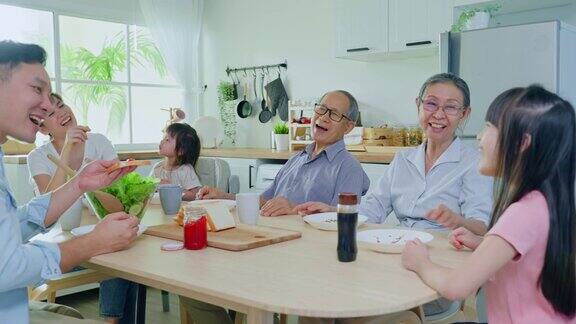 亚洲大家庭在家里的餐桌上一起吃午饭年长的爷爷奶奶、年轻的夫妇和年幼的女儿感到高兴在家里享受吃面包活动关系