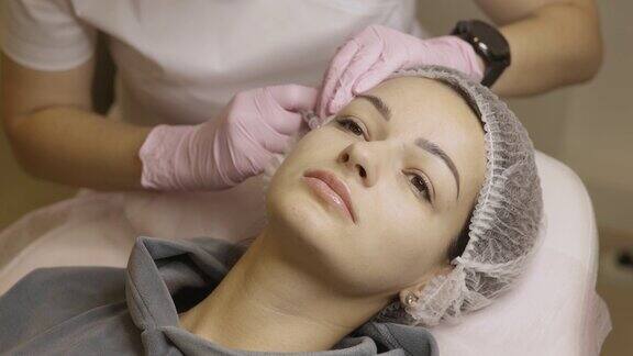 在美容院进行面部整形手术一位美容师医生在一位年轻美女的脸上注射药物消脂biorevitalization美容有选择性的重点