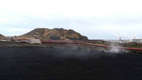 冬季多云天气冰岛雷克雅尼半岛Grindavík附近的Svartsengi地热发电厂前用蒸汽输送热水的红色管道