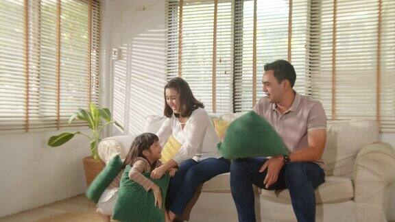 快乐快乐的亚洲家庭妈妈爸爸和孩子的女儿有乐趣与枕头打架享受一起在客厅在家里笑