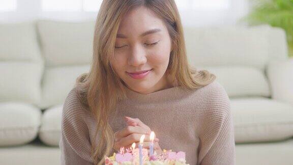 一位年轻的亚洲女子在吹灭蛋糕上的蜡烛前正在许愿