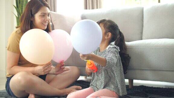 妈妈和可爱的小女孩在家里客厅的沙发上玩气球