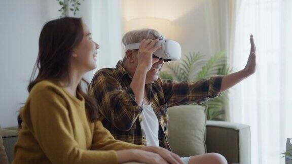 快乐的亚洲老人在与家人的空闲时间在客厅使用虚拟现实模拟器