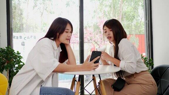 亚洲女子和朋友在咖啡店用智能手机自拍