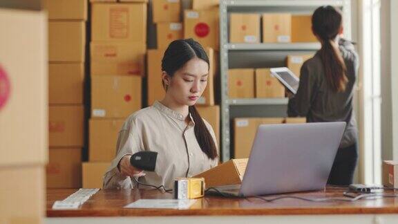 一名亚洲女性在网上商店仓库工作用笔记本电脑包裹盒上架网上电子商务零售小生意