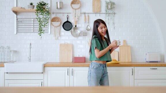 女子在厨房举着杯子跳舞