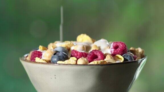 把牛奶倒进装满脆脆的格兰诺拉麦片的碗里健康脆片配覆盆子和蓝莓