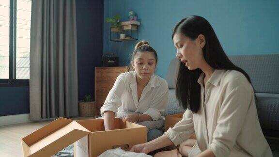 两个亚洲妇女把旧衣服放进纸板箱里她们要捐赠