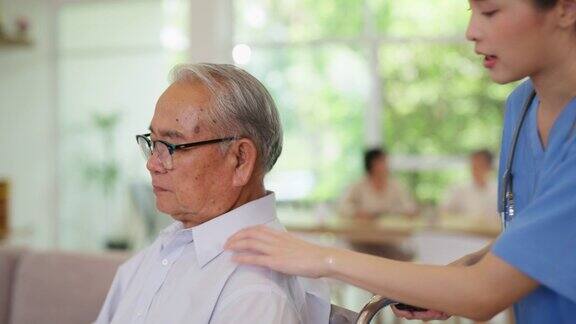 年轻的亚洲护理医生在养老院的客厅里推着坐在轮椅上的老人精神保健和健康护士带着微笑照顾老人和理疗