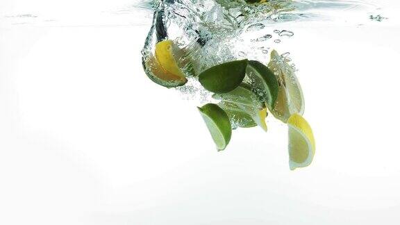 黄色的柠檬柠檬柠檬和绿色的柠檬柑橘aurantifolia水果落入水中的白色背景慢镜头4K