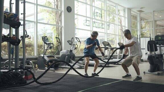 亚裔华人高级私人教练鼓励高级男子在健身房练习跳绳