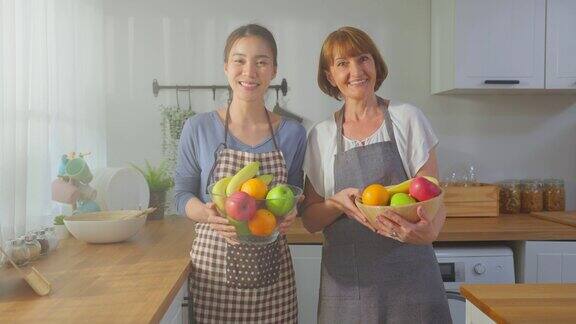 年轻女子和年长的祖母拿着一碗水果的肖像迷人美丽的女孩和年长成熟的母亲喜欢在家里吃干净的蔬菜来保持健康饮食与健康食品概念