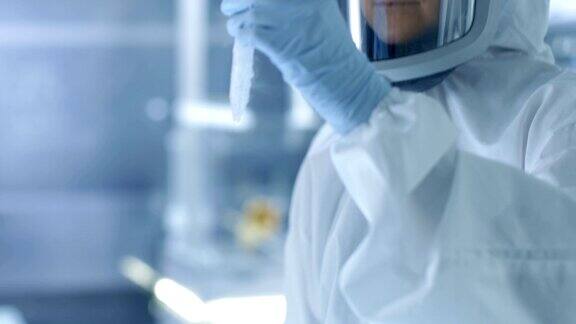 医学病毒学研究科学家工作在防护服和口罩她检查试管与分离病毒串从冰箱盒子她在一个无菌的高科技实验室研究机构工作