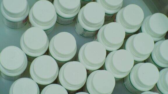 现代制药生产装有药品的塑料瓶在传送带上移动前视图特写镜头