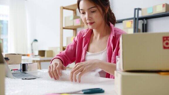 年轻的亚洲企业家女商人包装产品在纸板箱交付客户工作在家庭办公室