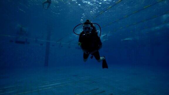 潜水员戴着潜水面罩和潜水装备在深水池中游泳