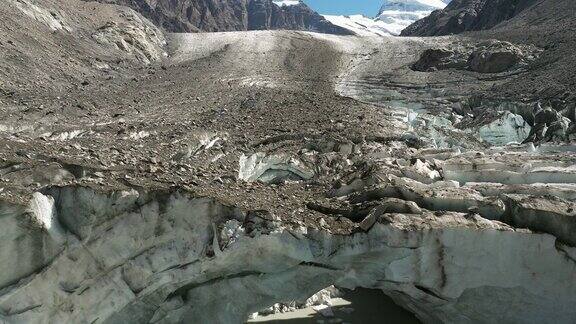 无人机俯瞰冰柱之间的寒冷池塘背景是粗糙的岩石山景观