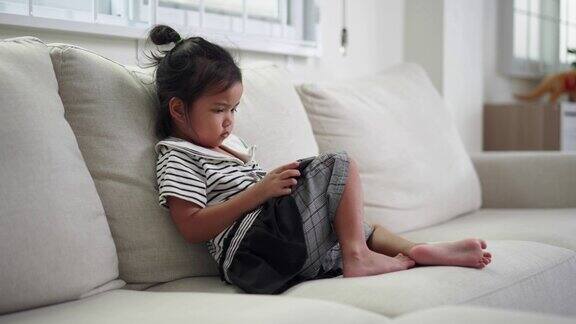 小女孩坐在沙发上玩手机游戏在客厅用智能手机