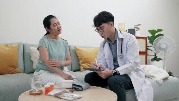 年轻的亚洲男性医生询问并记录病人的情况