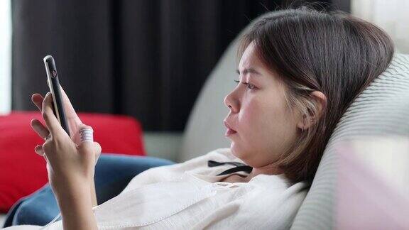 靠近眼睛亚洲女人放松玩智能手机在客厅