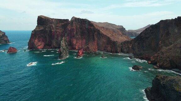 大西洋海岸线上有红色的悬崖、岩石、蓝绿色的海浪和无人机产生的泡沫葡萄牙马德拉岛令人叹为观止风景景观视频