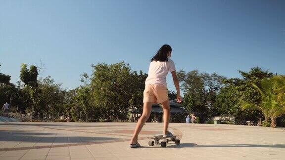 亚洲女孩在公园户外玩滑板阳光明媚积极的生活方式