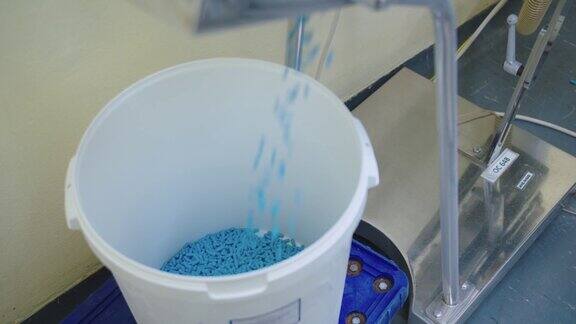人造的蓝色胶囊正落入容器中药品生产阶段:药品生产的阶段