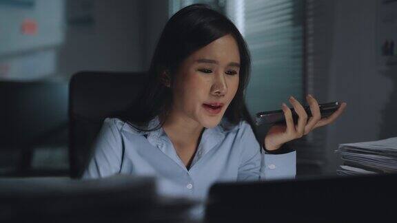 愤怒愤怒的年轻亚洲女商人在电话上讨论问题错误的文书坐在办公室的书桌在晚上严肃的年轻女士打电话做手势表达负面情绪