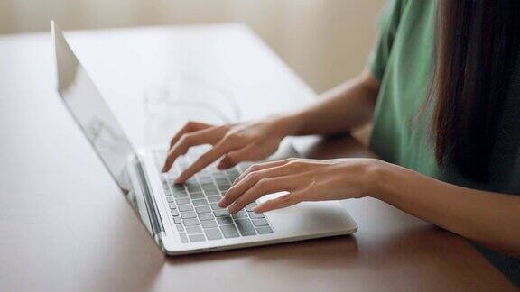 女人的手在家里的笔记本电脑键盘上打字