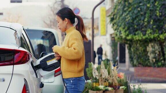 MS中年妇女正在给一辆电动汽车充电
