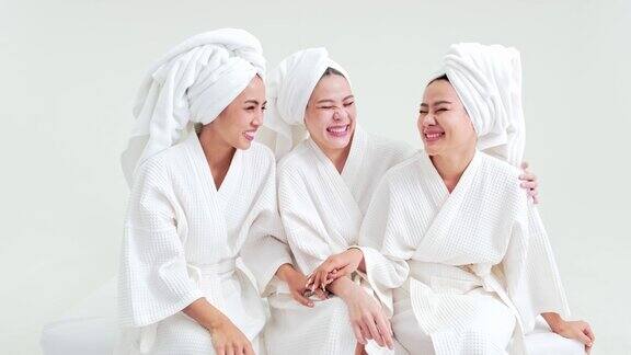 三个年轻的亚洲女人穿着浴袍头上缠着毛巾聊得很开心穿着长袍和毛巾的女性朋友们在豪华酒店的水疗后穿着毛巾和浴袍享受乐趣