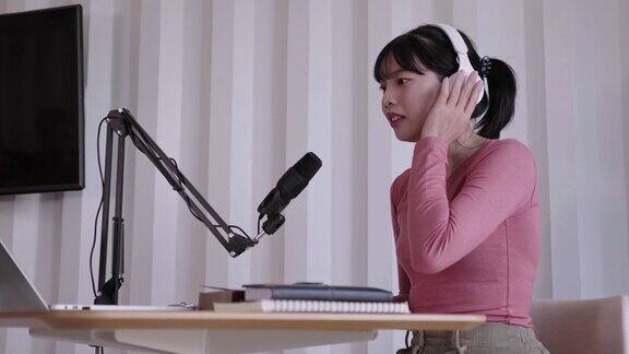 快乐的亚洲妇女设置播客工作室戴着耳机录制播客与麦克风专业设备的广播在线直播在家庭工作室