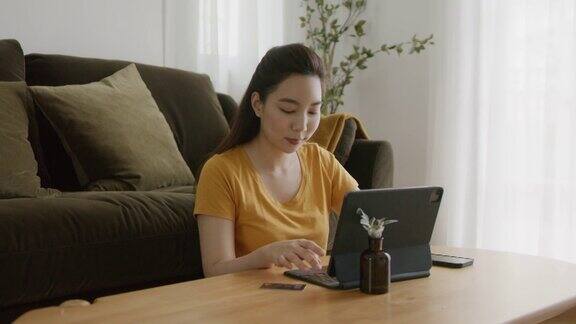年轻的亚洲妇女购物笔记本电脑与信用卡