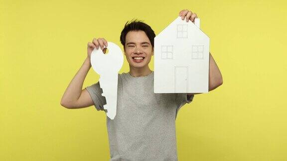 快乐兴奋的年轻人手里拿着大大的纸钥匙和房子的模型