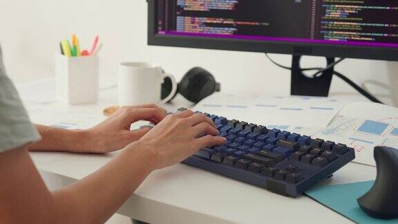 特写年轻的亚洲女孩IT开发程序员在键盘上打字编码编程在电脑显示器和笔记本电脑上修改数据库代码桌子上的工作室在家庭办公室