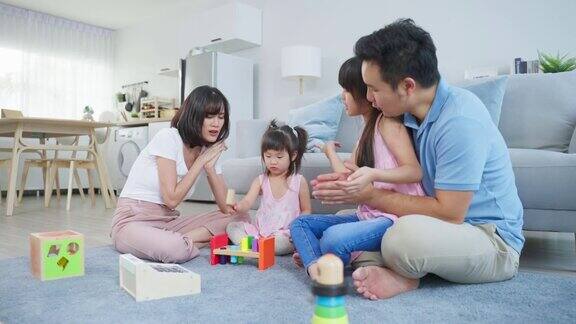 亚洲幸福家庭坐在地板上在客厅里一起玩玩具漂亮的父母和父母花时间和年轻的小女孩在家里家庭活动关系概念