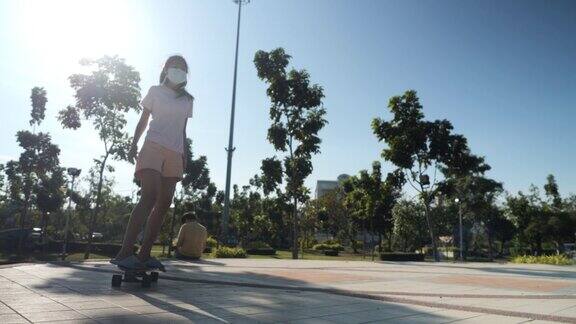 亚洲女孩在公园户外玩滑板阳光明媚积极的生活方式