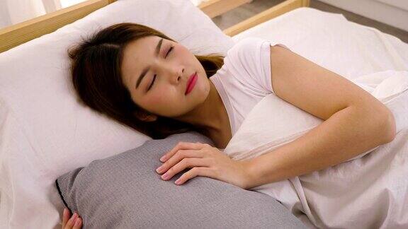年轻美丽的亚洲女人醒来伸展在她的床上在家
